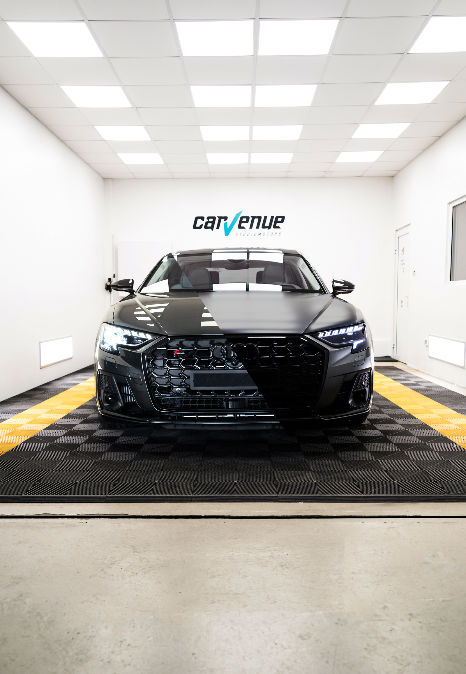 Black Audi S8 seen head-on in the CarVenue studio, one half of the body glossy and the other matte