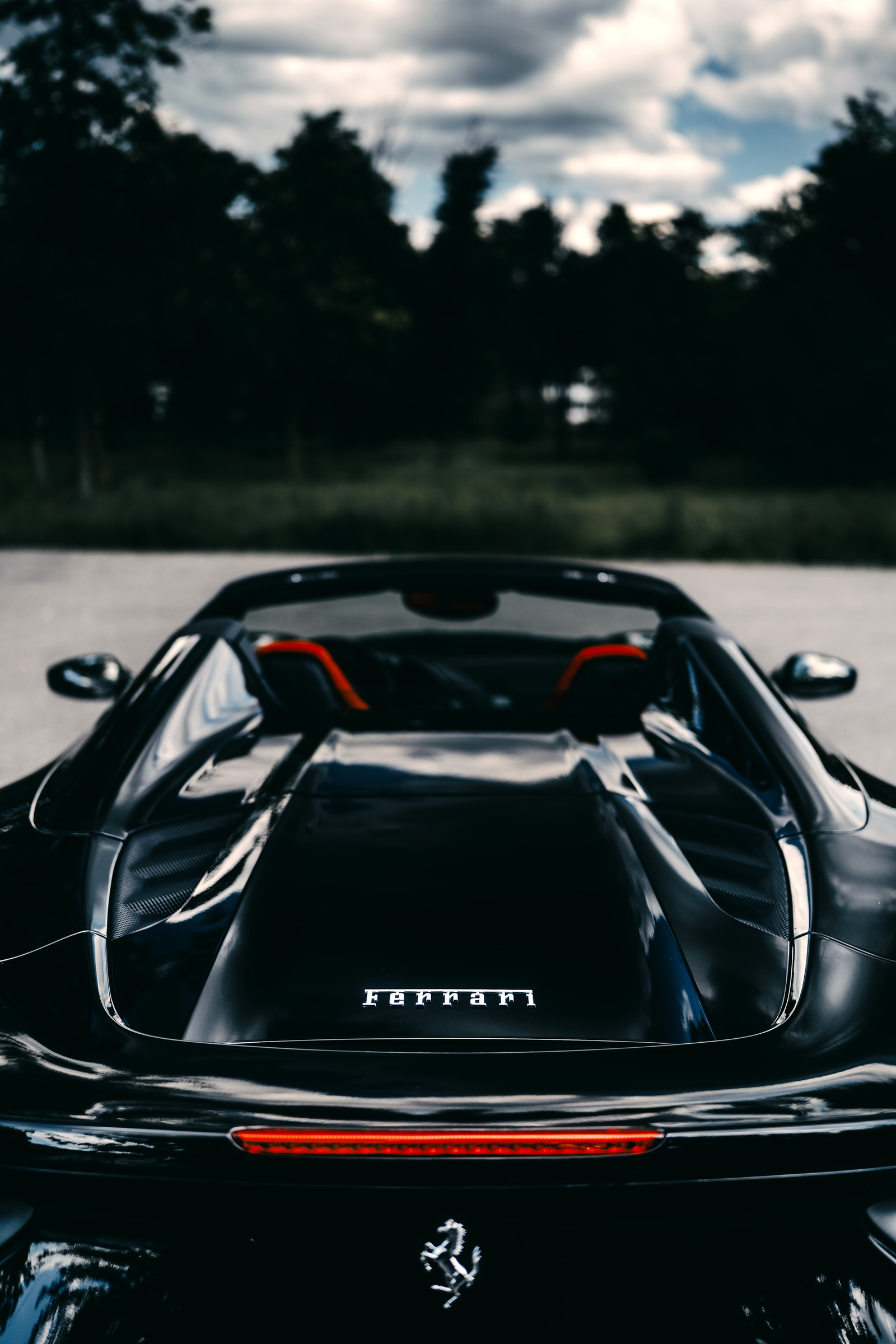 Glossy rear of an open-top black Ferrari 488 Spider, with the Ferrari script, red third brake light and prancing horse